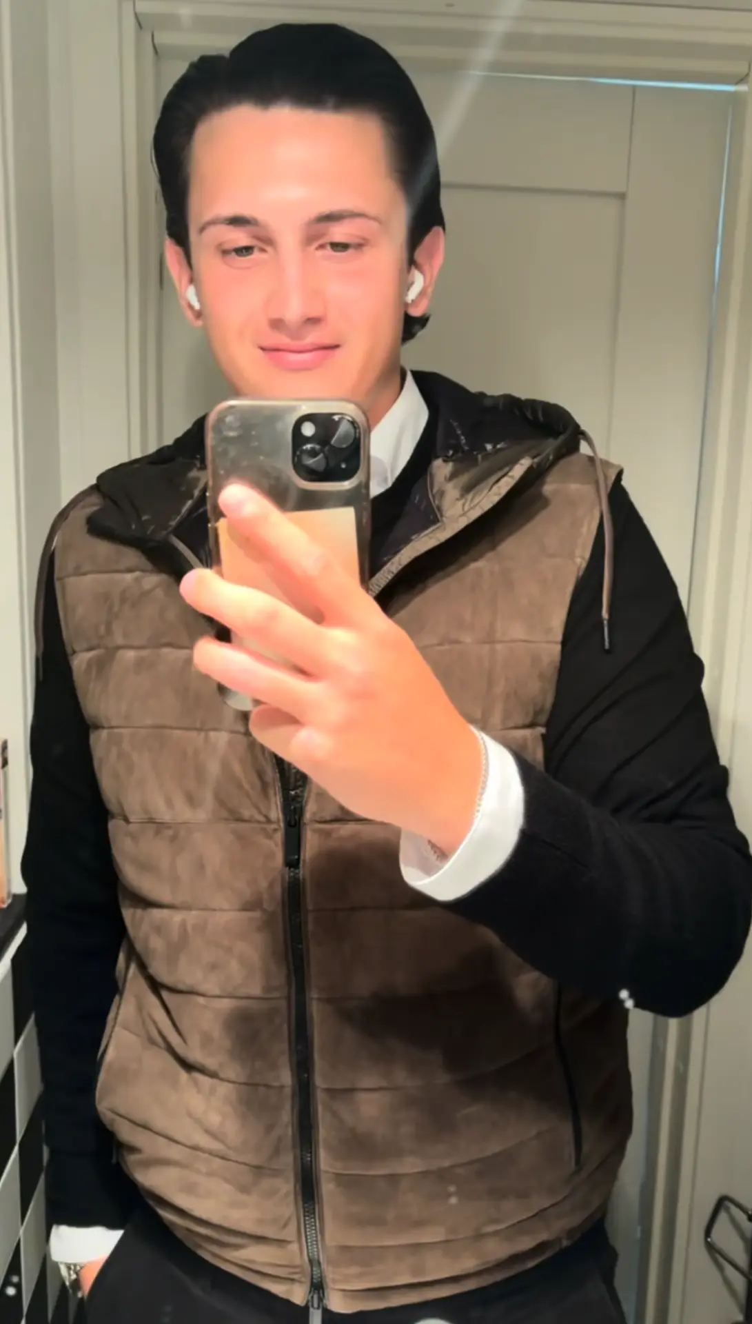Adrian i brun quiltad väst över vit skjorta och svart hoodie